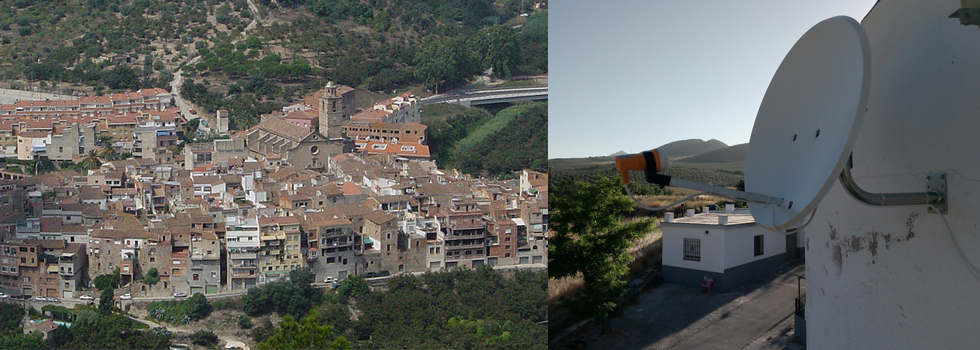 Vista aérea de una pequeña ciudad con edificios agrupados a la izquierda y una antena parabólica montada en una pared blanca a la derecha.